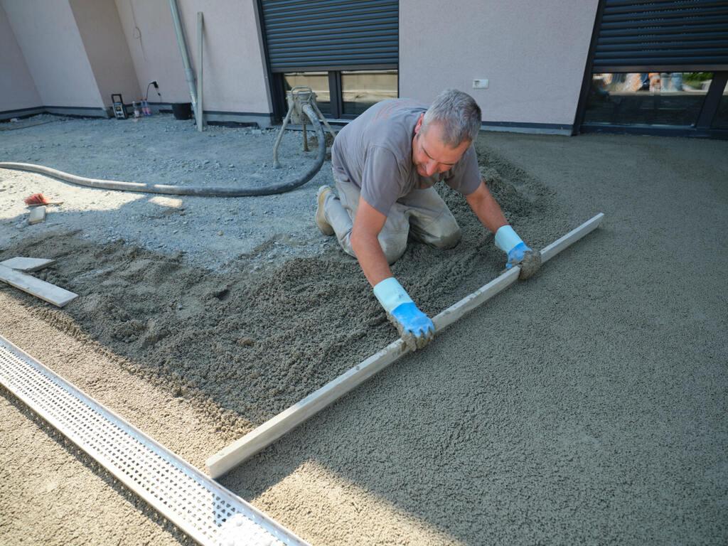 Concrete crew finishing a sloped patio slab with a drain in Round Rock