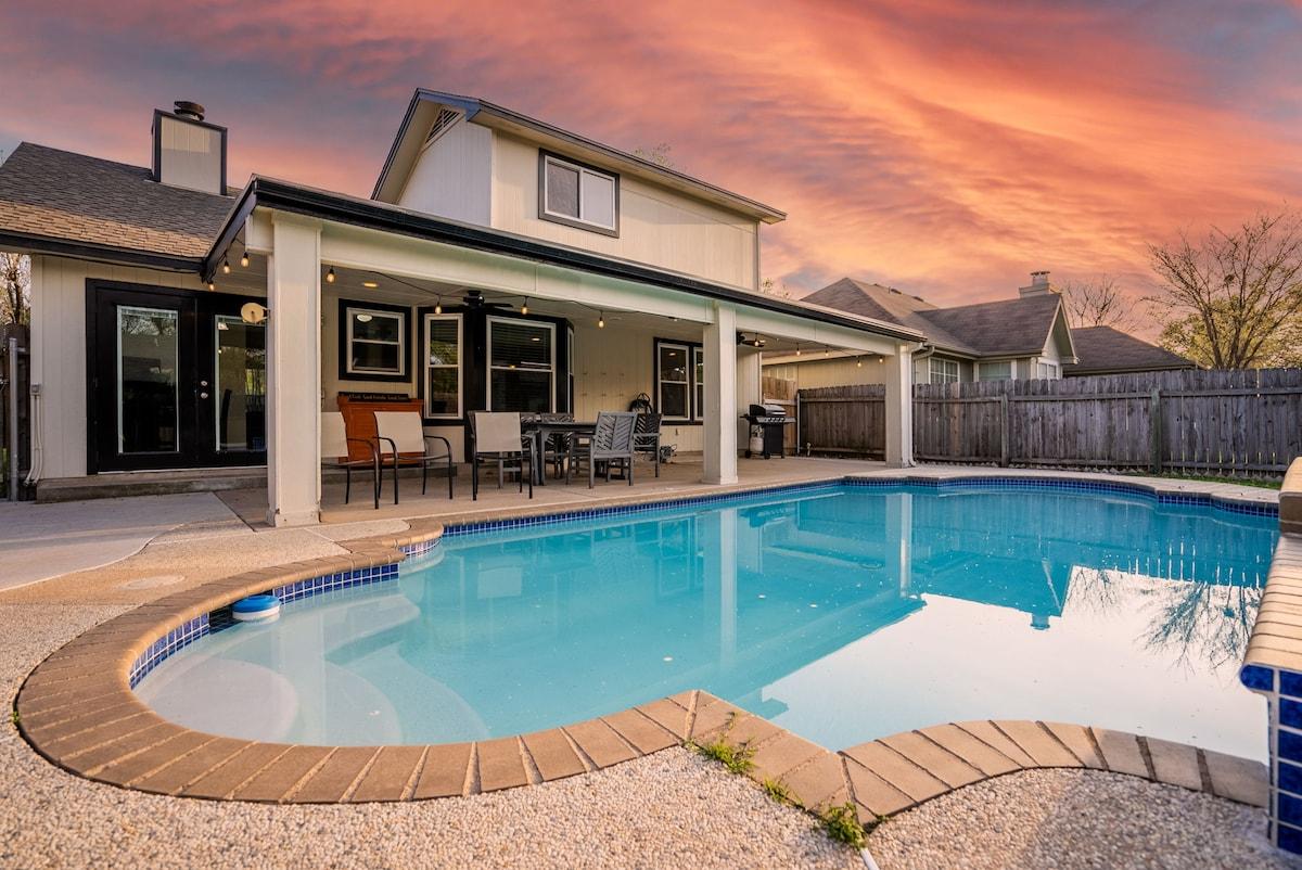 Insulated aluminum patio cover with ceiling fans and lighting over a two-story Round Rock backyard at dusk
