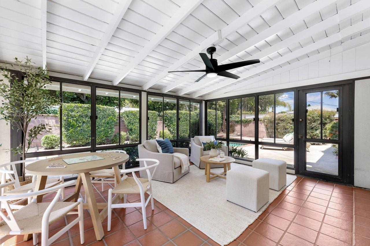 Interior of a sunroom with sliding glass walls, ceiling fan and tile floor