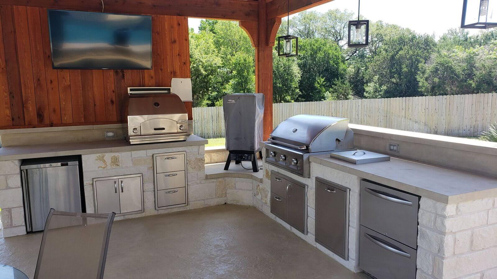 Outdoor kitchen with stone grill island under aluminum cover, Forest Creek, Round Rock