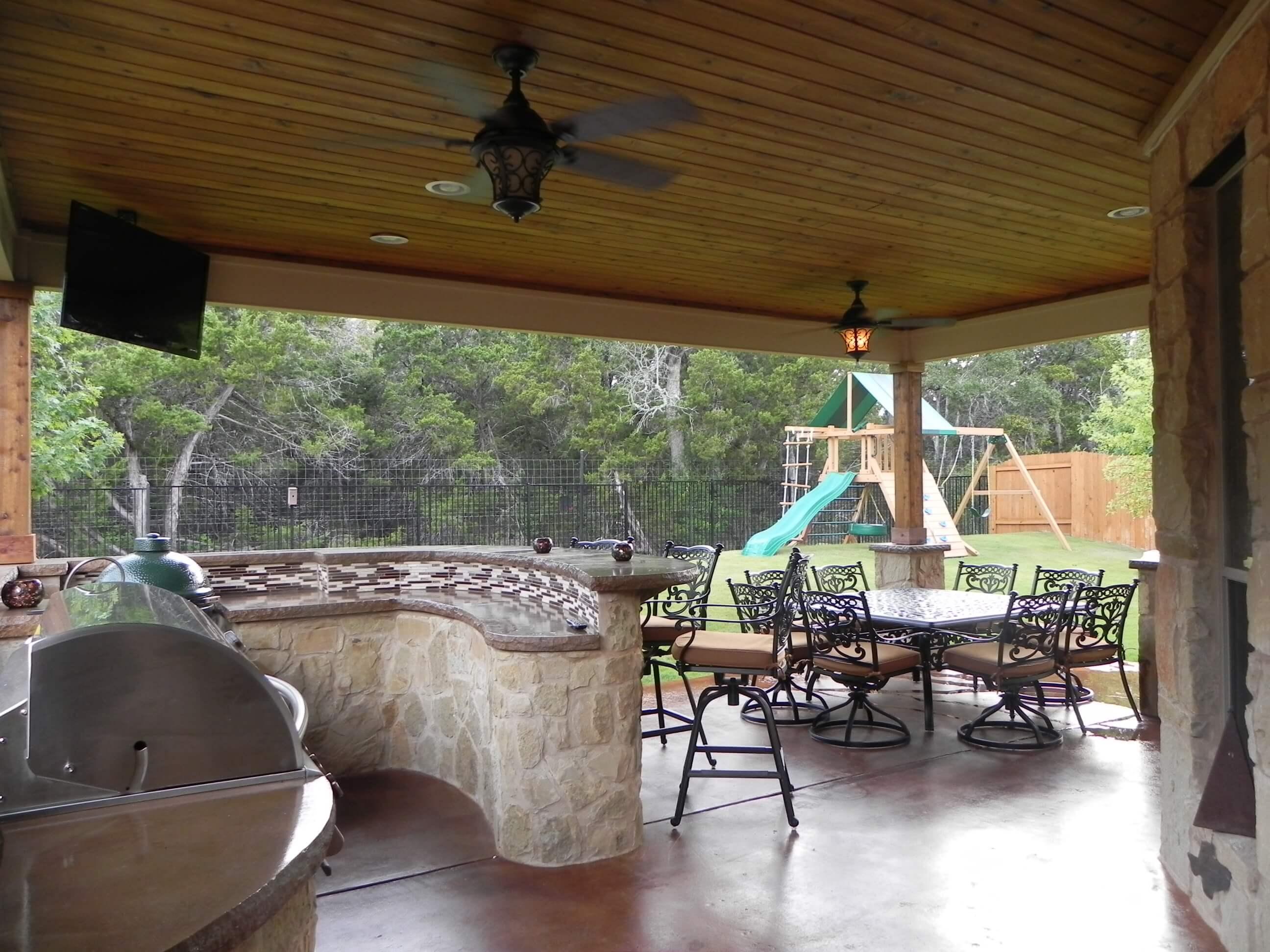 Outdoor kitchen with stone grill island under a covered patio in Forest Creek, Round Rock