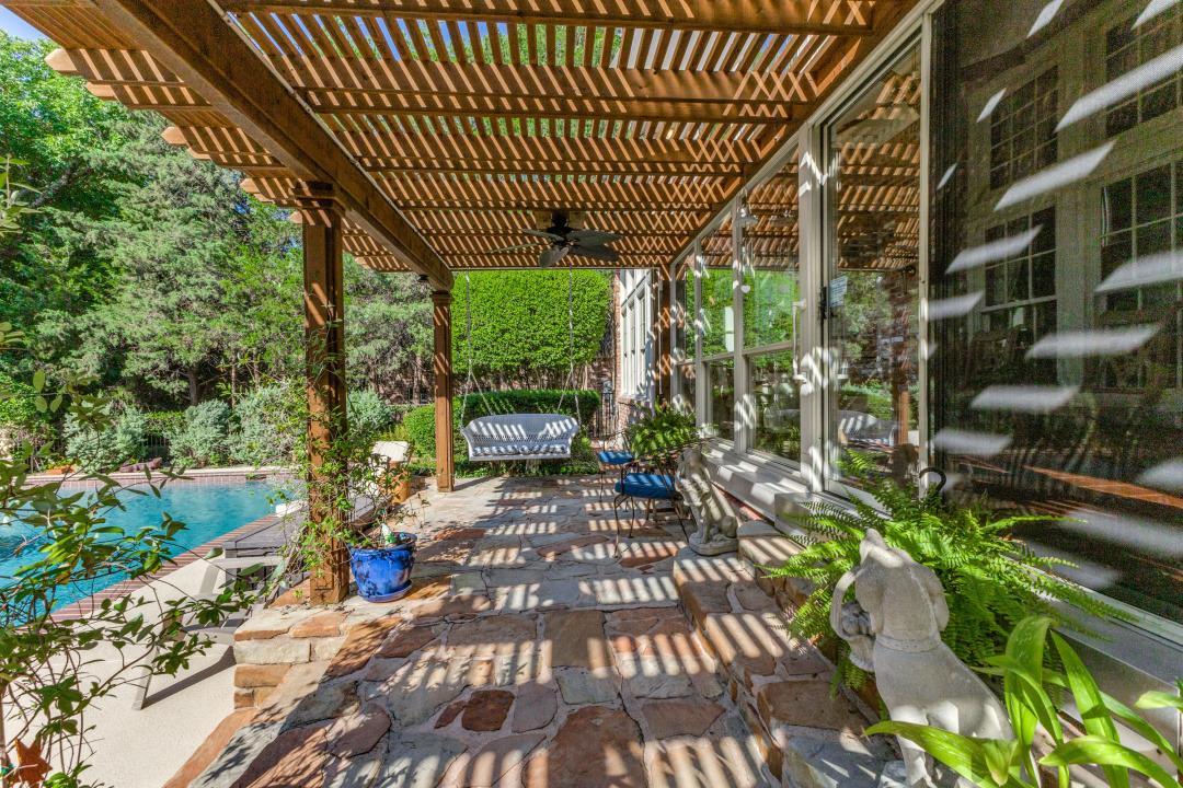 Pergola rafters casting striped shade across a stone patio in Round Rock
