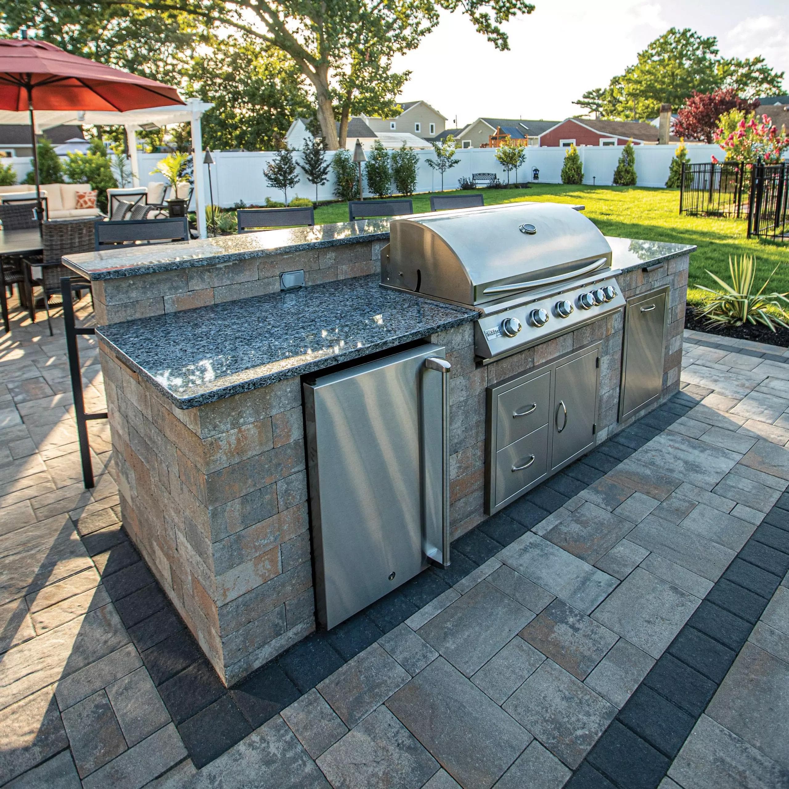 Stone outdoor kitchen island with a built-in grill and granite counter